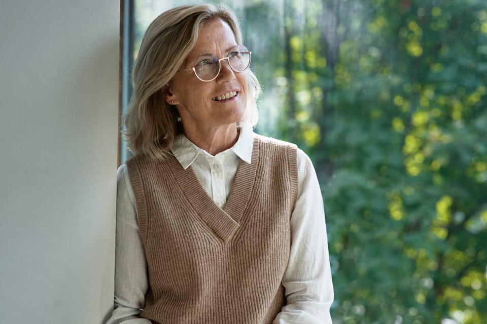 Bild av Lillemor Ivansson med en ljusbrun tröja och grönska i bakgrunden under fliken Lillemor Ivansson